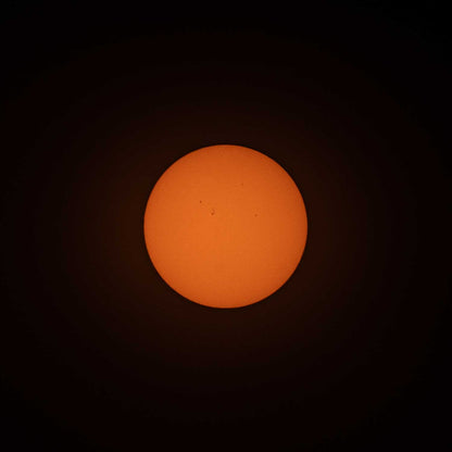 A photo of the sun, taken with ES-FLAR80640CF-iEXOS-100, showing the orange-colored sun with sunspots scattered across the visible surface of the sun